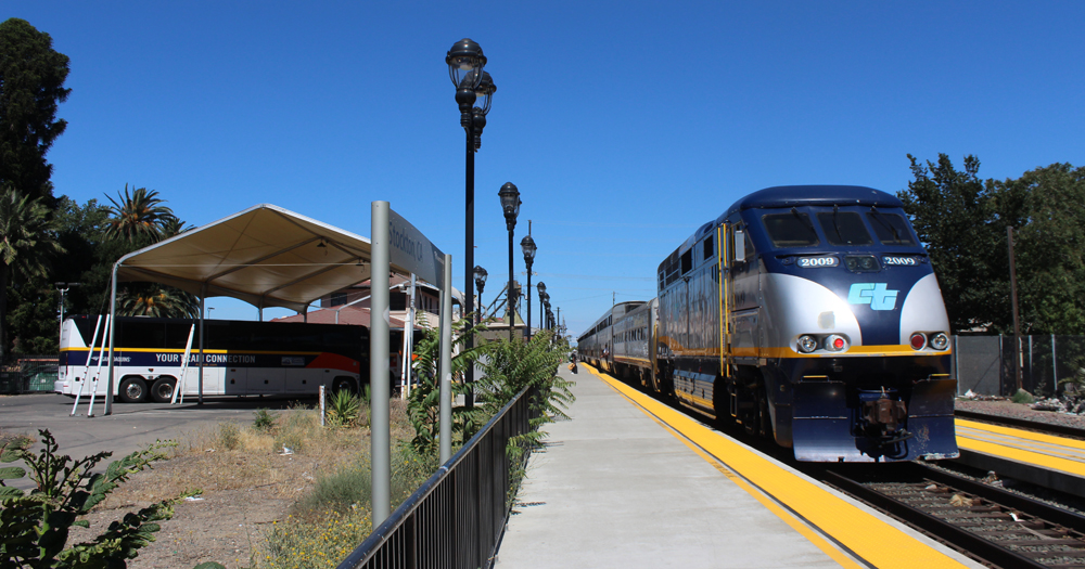 Passenger train stopped at station with bus waiting across platform