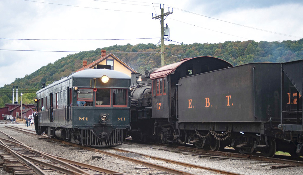 Green motorcar passes non-operating steam locomotive