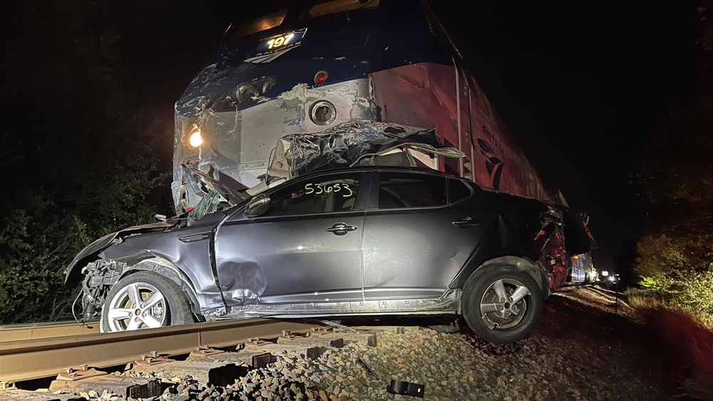 Damaged locomotive and automobile on railroad tracks