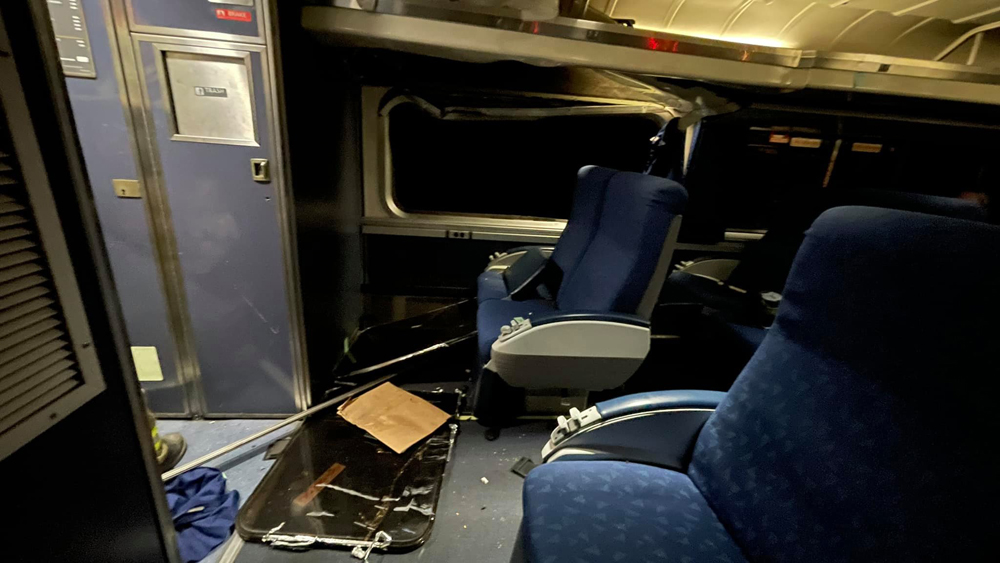 Interior of passenger car showing damage around window frame with window on floor