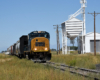 A locomotive hauls a freight train in a flat landscape.