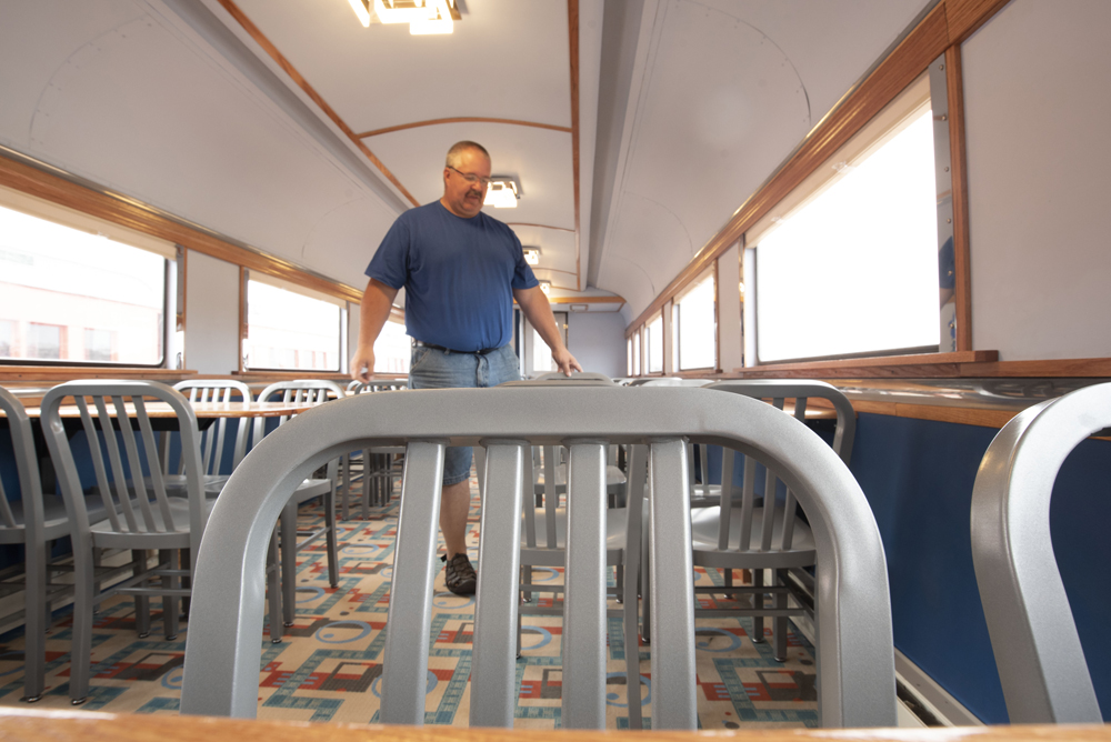 Man stands among dining tables in passenger car