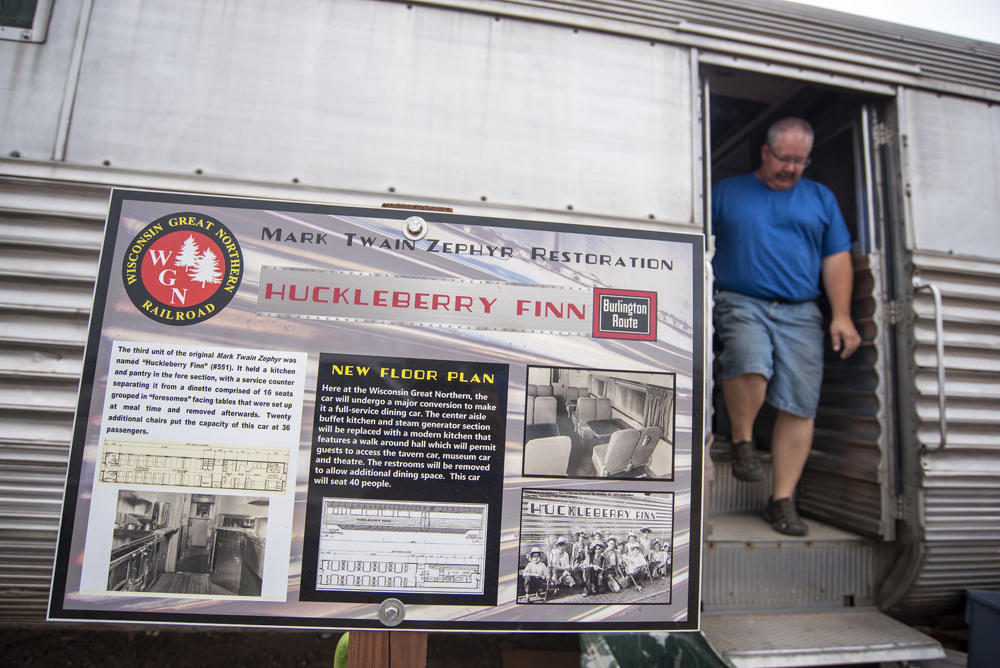 Sign explaining work on passenger car with man exiting from door behind