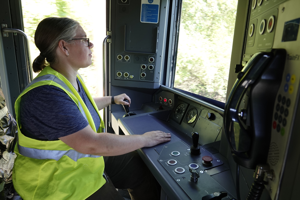 Woman in high-visibility vest at controls of railcar