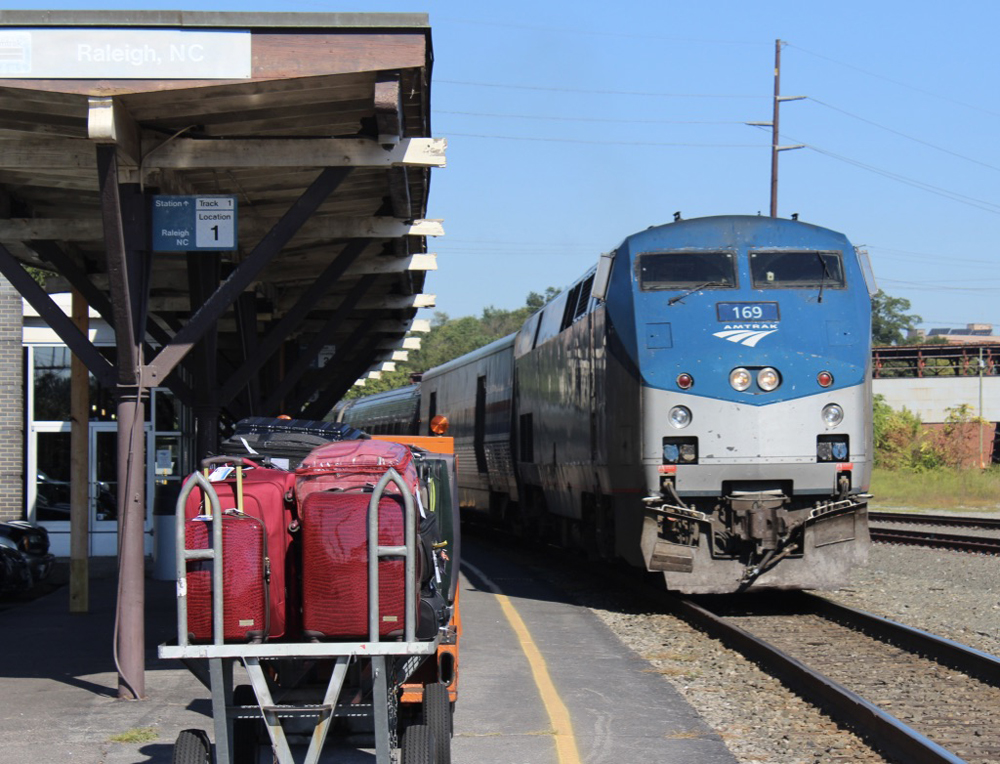 Passenger train arrives at station with baggage cart in foreground