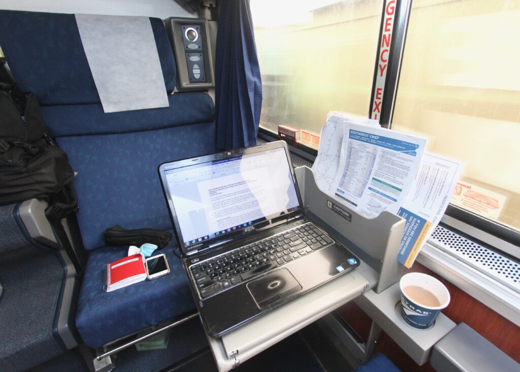 Objects in Amtrak roomette including computer, cellphone, schedule