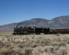 Steam train on hillside overlooking desert valley below