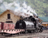 Rear view of a steam locomotive and tender in a rail yard.