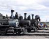 Four steam locomotives line for display in a rail yard.