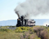 Double-headed steam passenger train high steps over the high plains.