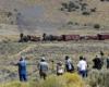 Steam hauled passenger train in open grassland.