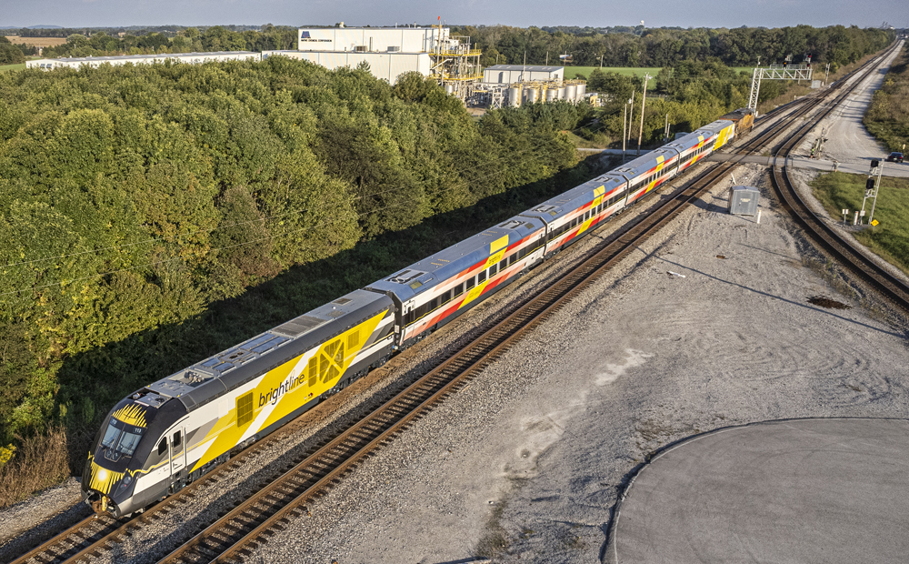 Aerial view of passenger equipment being pulled by freight locomotive