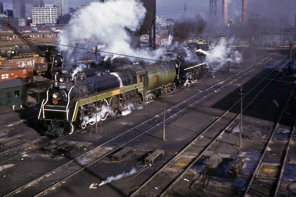 Green and black steam locomotive by steel water tower