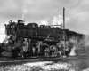 Steaming steam locomotive hooked up to stationary piping