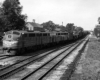 Streamlined diesel locomotives bring a freight train through town on a multiple track line