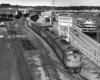 Streamlined diesel locomotives lead a train over a diamond crossing by a river