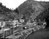 Rail yard and town along riverbank in narrow valley