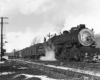 Man stands on steam locomotive tender in front of station in snow