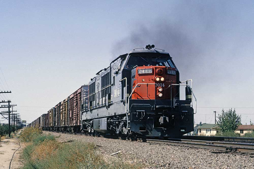 Gray and red diesel locomotive pulls stock cars