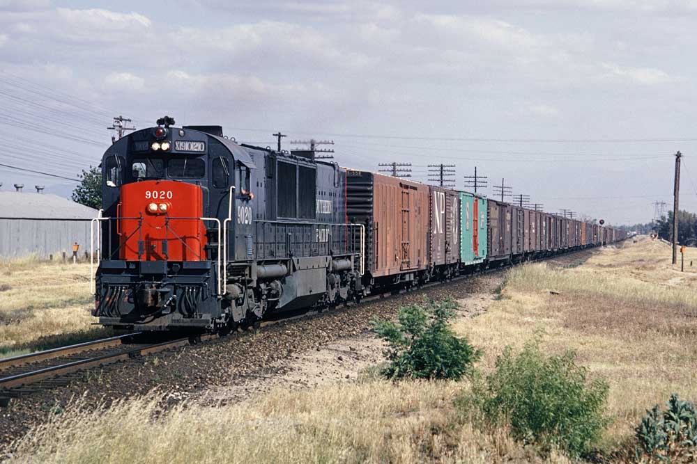 Gray and red diesel locomotive pulls box cars