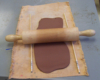 A rolling pin rolling out clay on a piece of canvas