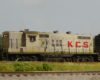 A white diesel with red “KCS” lettering pulls a boxcar