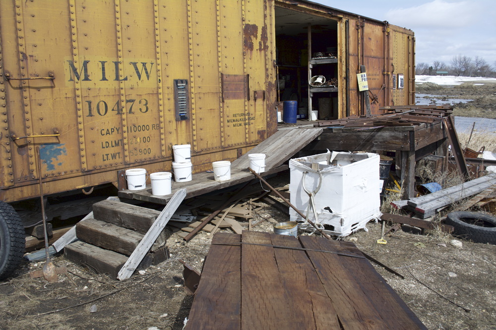 Old railroad ties and bridge walkway planks used as staircase and ramp to boxcar interior