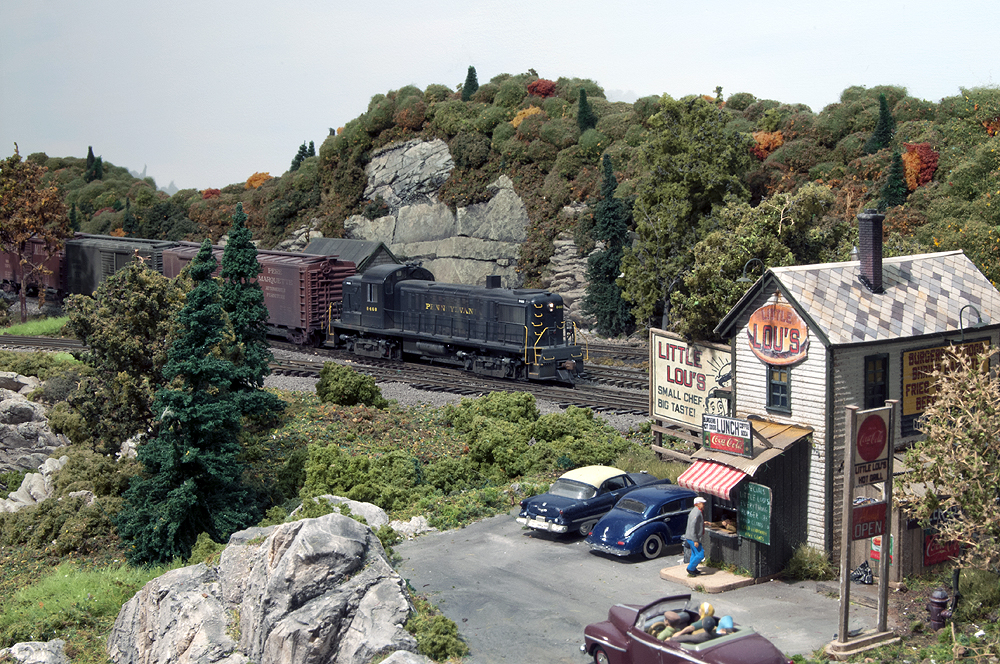 A train passes by a small restaurant on the mountainside