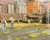 Two figures stand trackside while their steam locomotive rests by the yard office