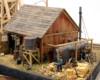 A worker carries freshly chopped firewood to a former locomotive boiler behind a mine building