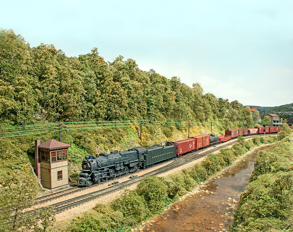 A train pulling a long line of cars traveling along a dense forest