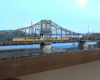 A yellow Union Pacific freight train crosses a bridge on a model train layout.