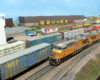 Freight trains in a yard with a white windowed tower in the background.