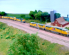 Two freight trains meet in a rural scene on a model train layout.