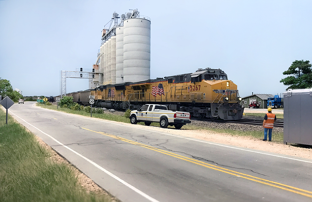 Two Union Pacific locomotives lead a train near a grain elevator.