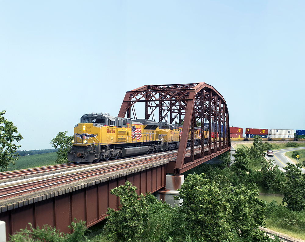 Yellow Union Pacific locomotives lead an intermodal train over a double-track bridge.