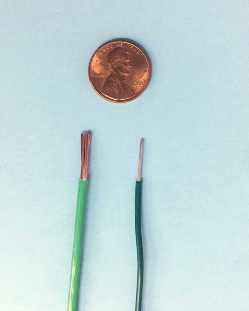 Two wires next to a penny for size comparison.