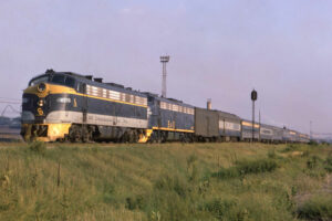 blue and yellow locomotive leading train
