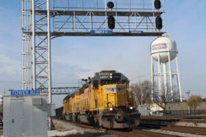 yellow locomtive beneath signal bridge