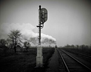 steam train in distance coming at you with signal in foreground