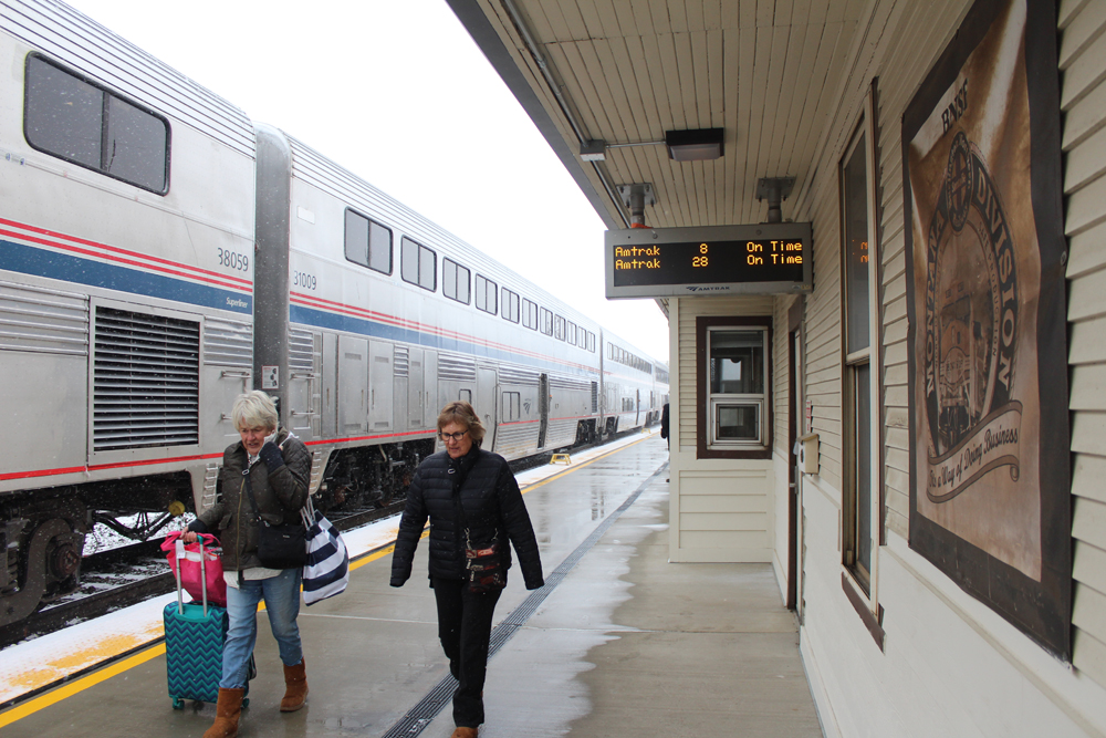 Two people walking on station platform next to passenger train