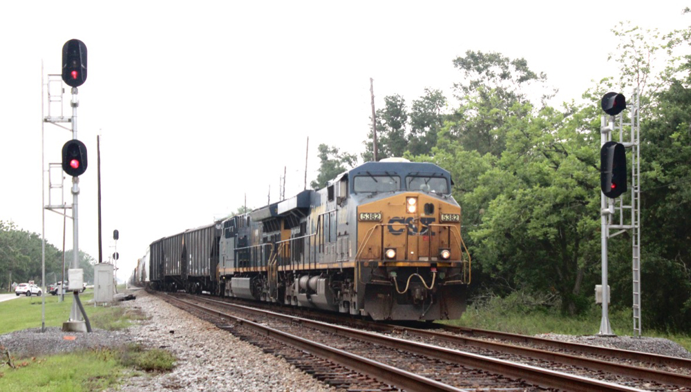 Freight train with blue and yellow engine leaving main line