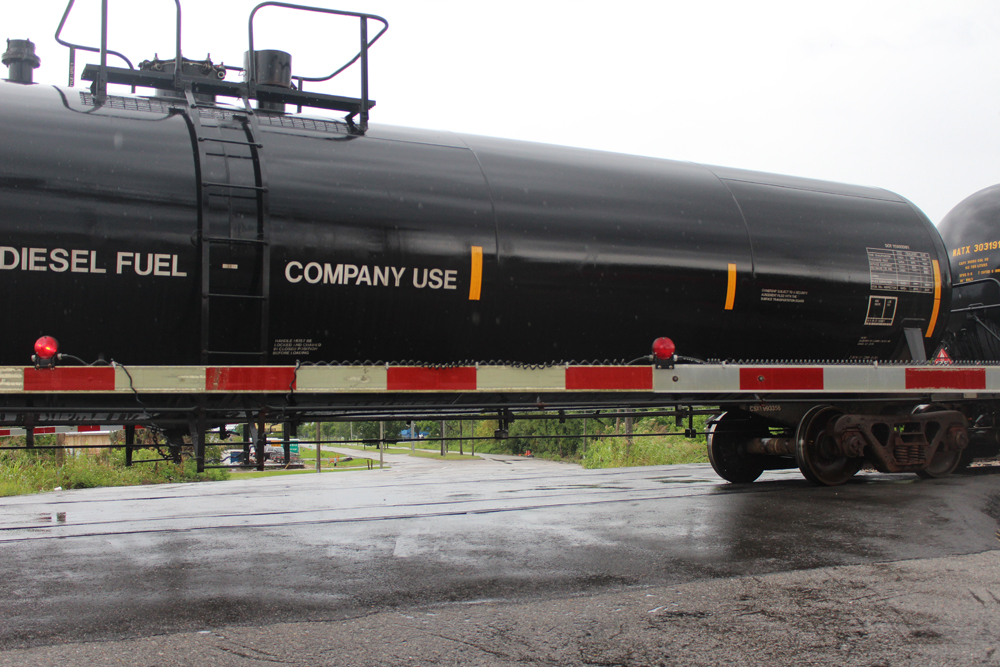 Tank car blocking street behind lowered crossing gate