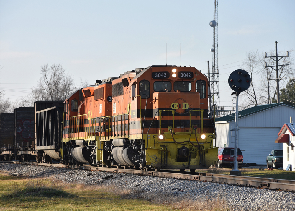 Orange and black locomotives pass color position signal