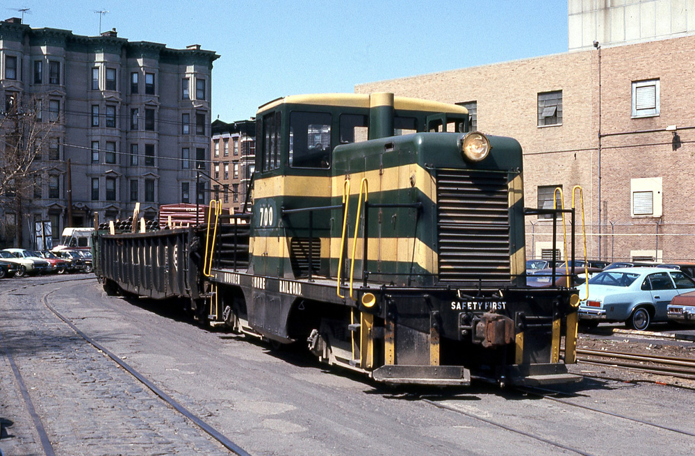 Green and yellow locomotive running in middle of street