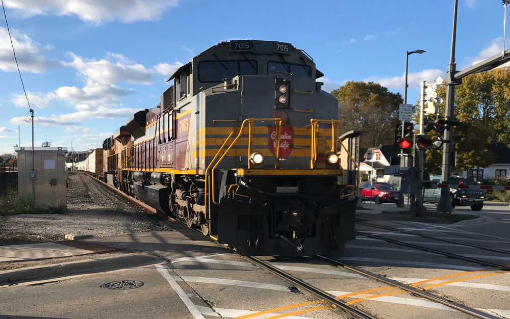 Maroon, gray and yellow locomotive leading train