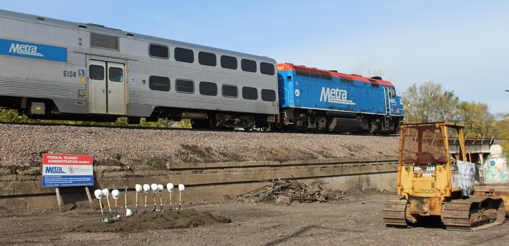 Commuter train passes shovels and hard hats awaiting groundbreaking ceremony