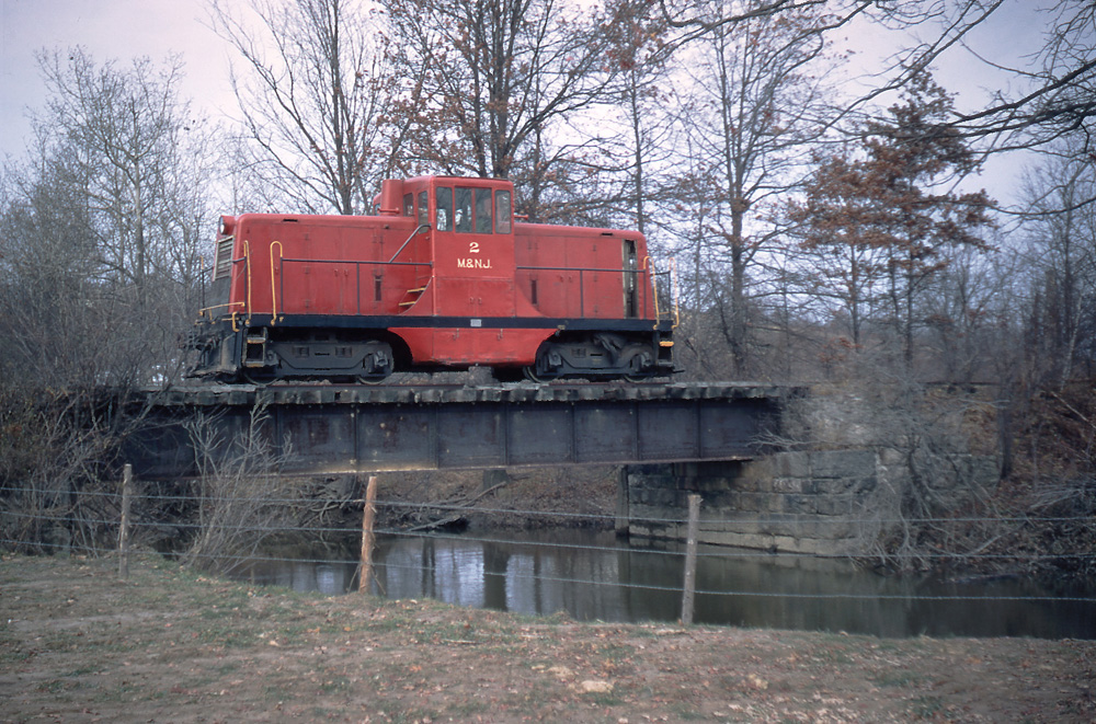 Red center-cab locomotive on bridge
