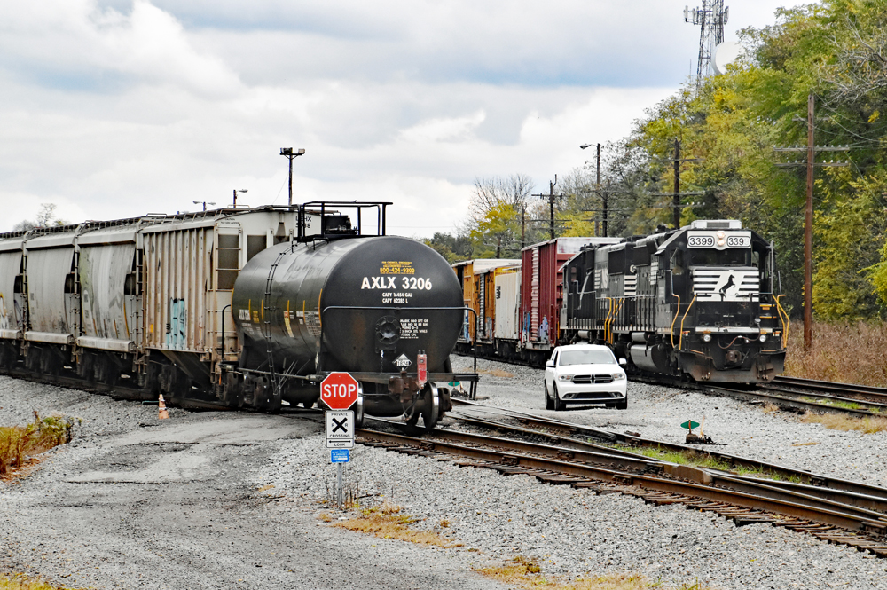 Train departs yard as another train waits