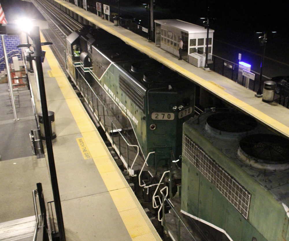 Overhead view of black and green locomotives at passenger station